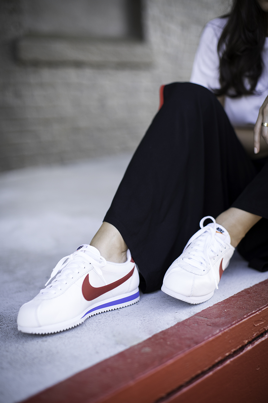 Detail shot of Liv wearing Nike Cortez, Forever 21 black red palazzo track pants and cropped t-shirt.