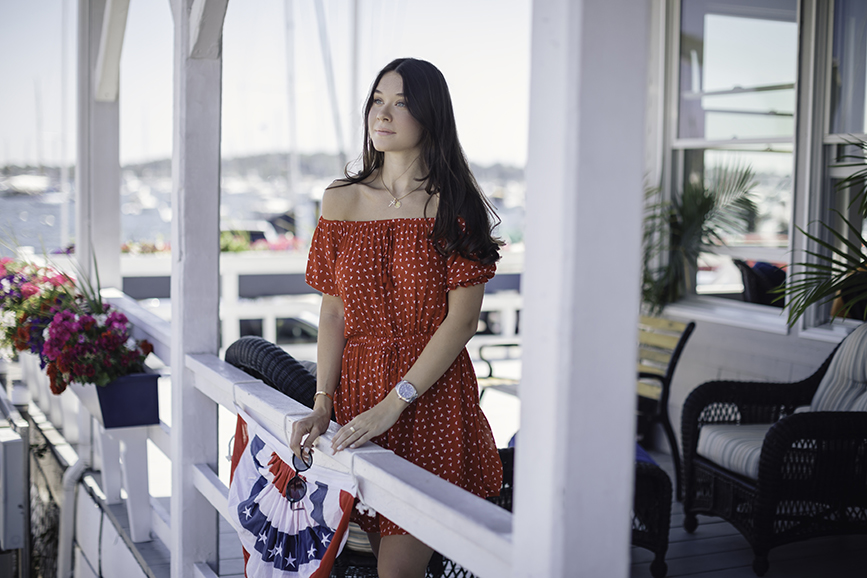 Liv on a deck in Newport Rhode Island just steps away from the Newport Marriott wearing an off the shoulder dress by Faithful the Brand. 