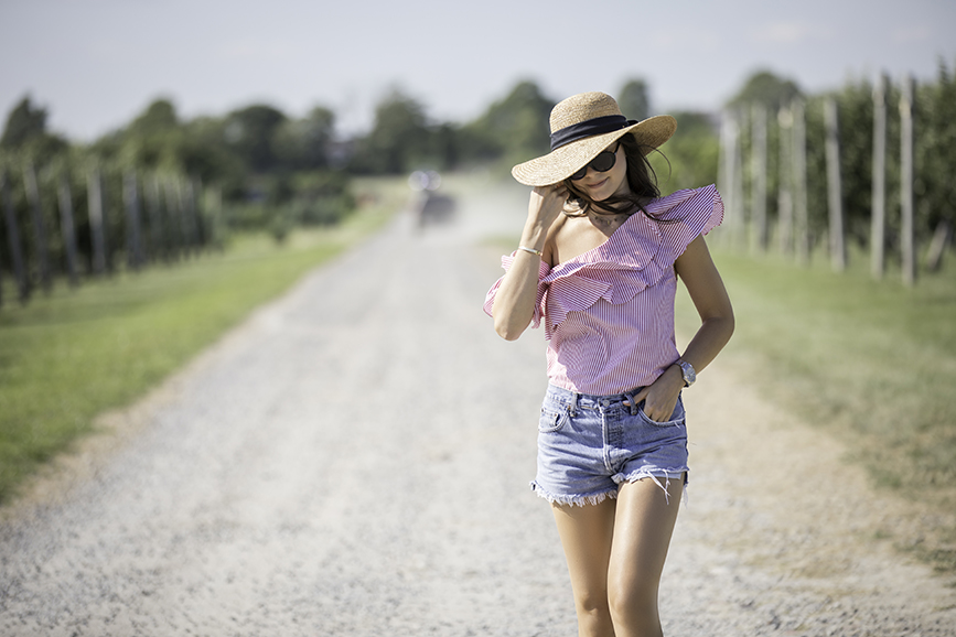 Liv walking at the Sweetberry Farm in Newport Rhode Island about to pick raspberries and strawberries wearing vintage Levi shorts by Re Done, a L'academie top, and a Scala hat