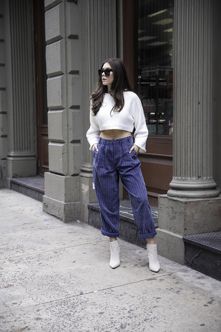 Liv Micheli standing in the streets of SoHo wearing OFF WHITE c/o Virgil Abloh x Warby Parker Medium sunglasses, Urban Outfitters Roll neck Cropped Sweater, Silence + Noise Relaxed-Fit trousers and Kenneth Cole boots.