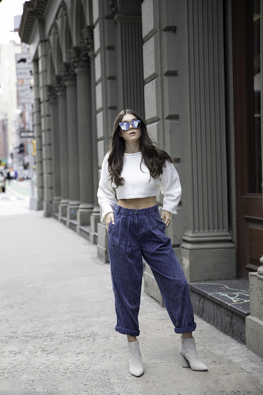 Liv Micheli standing in the streets of SoHo wearing OFF WHITE c/o Virgil Abloh x Warby Parker Medium sunglasses, Urban Outfitters Roll Kneck Cropped Sweater, Silence + NoiseRelaxed-Fit trousers and Kenneth Cole boots.