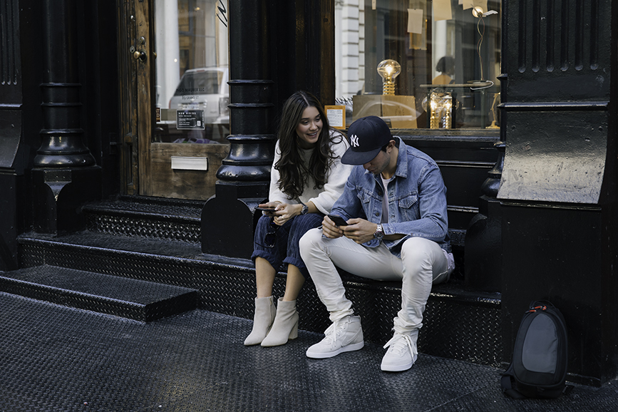 Liv Micheli and her brother, Paul Micheli sitting and laughing in the streets of SoHo. Liv is wearing OFF WHITE c/o Virgil Abloh x Warby Parker Medium sunglasses, Urban Outfitters Roll neck Cropped Seaters, Silence + Noise Relaxed-Fit trousers and Kenneth Cole boots. Paul is wearing John Elliott Cast 2 pants, John Elliott x Nike Sneakers, John Elliott Classic Crew Neck shirt, vintage Levis Denim Jacket, and a Yankee fitted hat.